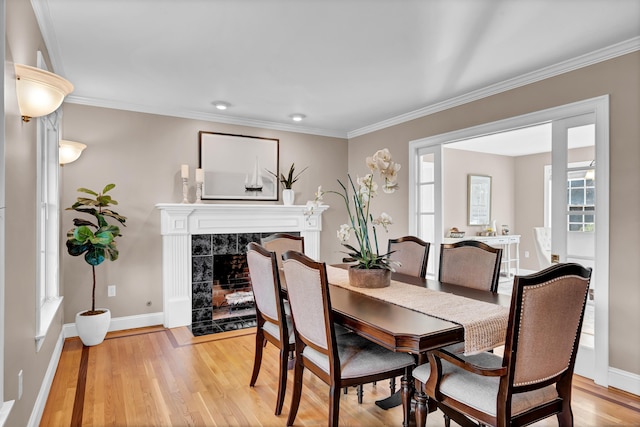 dining space featuring a fireplace, ornamental molding, and light hardwood / wood-style flooring