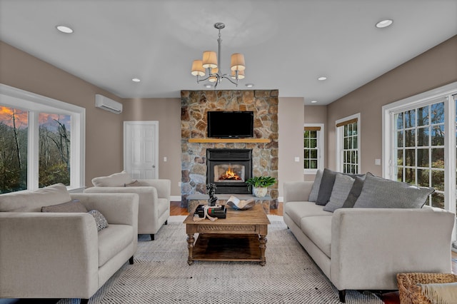 living room featuring light wood-type flooring, an inviting chandelier, a wealth of natural light, and a stone fireplace