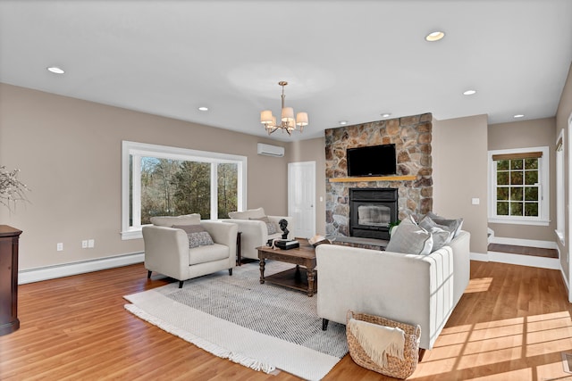 living room featuring a fireplace, light hardwood / wood-style floors, baseboard heating, and an inviting chandelier