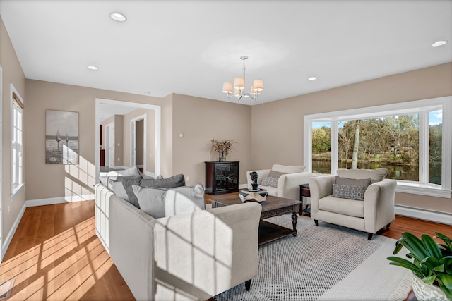 living room with a wealth of natural light, light hardwood / wood-style flooring, a chandelier, and a baseboard radiator