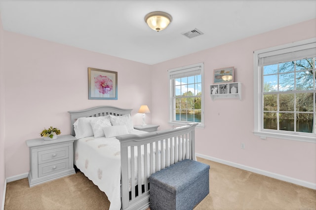 bedroom featuring light carpet and a water view