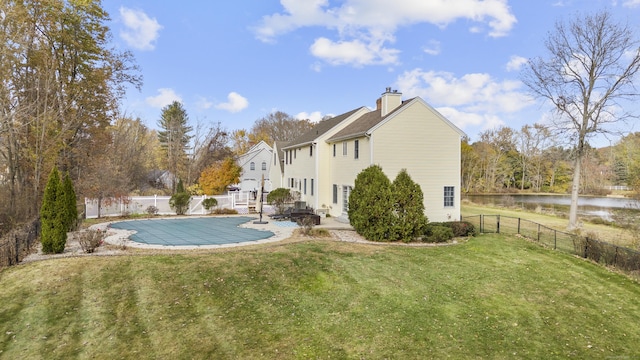 back of house with a yard, a water view, a covered pool, and a patio area