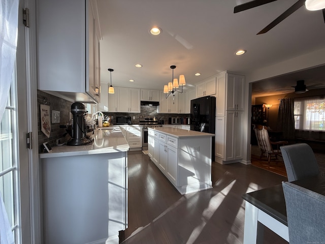 kitchen with hanging light fixtures, black refrigerator, and white cabinets