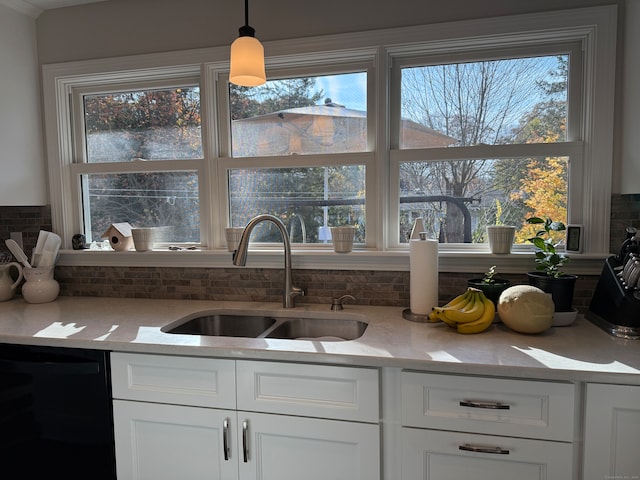 kitchen featuring black dishwasher, white cabinets, sink, backsplash, and decorative light fixtures