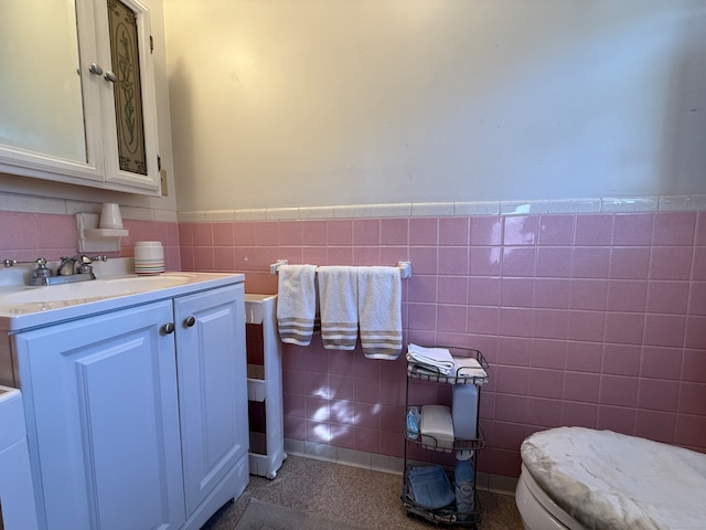 bathroom featuring vanity, toilet, and tile walls