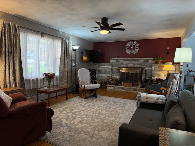 living room featuring a baseboard radiator, hardwood / wood-style floors, ceiling fan, and a fireplace