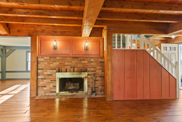 unfurnished living room featuring a fireplace, hardwood / wood-style flooring, beam ceiling, and wood ceiling