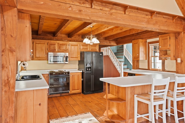 kitchen featuring light wood-type flooring, hanging light fixtures, black appliances, and kitchen peninsula