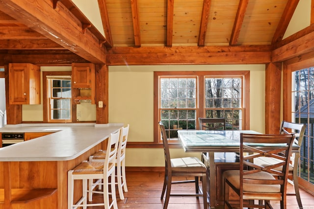 dining area with light hardwood / wood-style flooring, vaulted ceiling with beams, and wooden ceiling