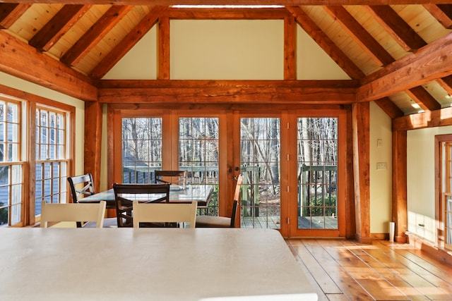 unfurnished dining area featuring high vaulted ceiling, light hardwood / wood-style floors, and beamed ceiling