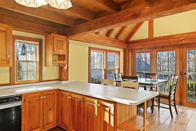 kitchen featuring light hardwood / wood-style floors, vaulted ceiling with beams, wood ceiling, kitchen peninsula, and a kitchen breakfast bar