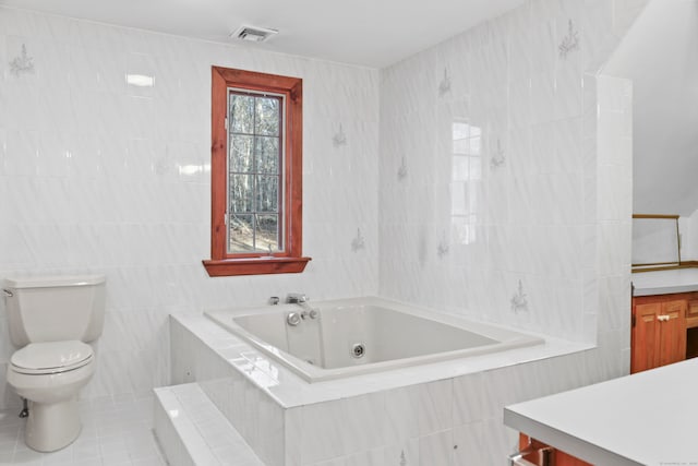 bathroom with a relaxing tiled tub, vanity, tile patterned floors, toilet, and tile walls