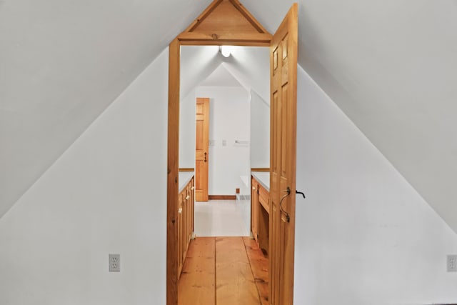 hallway with light hardwood / wood-style flooring and vaulted ceiling