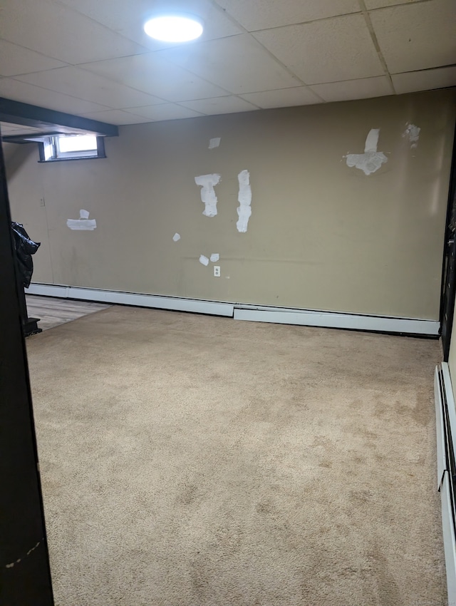 basement featuring a baseboard radiator, carpet floors, and a drop ceiling