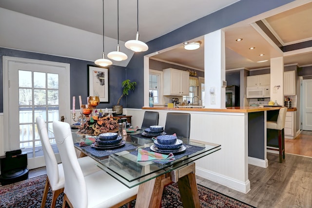 dining area featuring light hardwood / wood-style flooring, sink, and crown molding