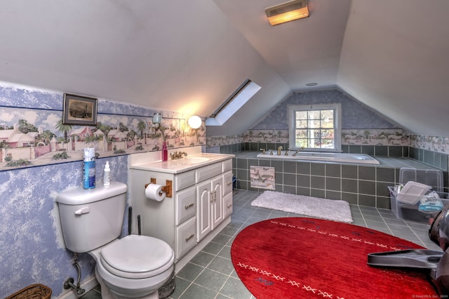 bathroom featuring toilet, vanity, vaulted ceiling with skylight, and a relaxing tiled tub