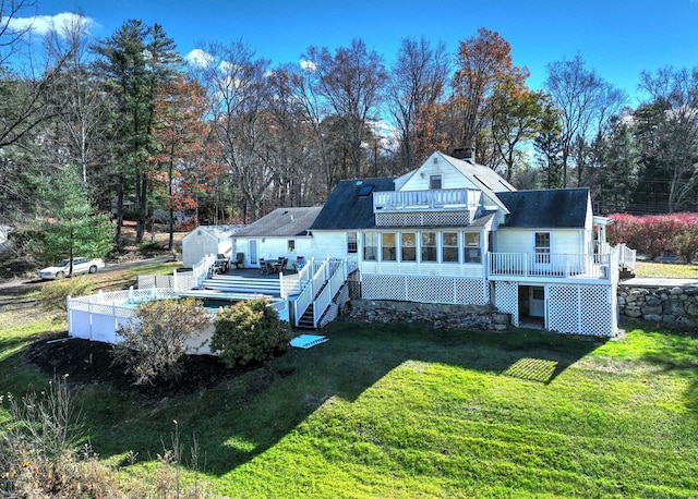 rear view of house featuring a lawn and a deck