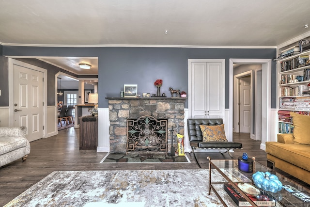 living room featuring built in shelves, a fireplace, dark hardwood / wood-style floors, and crown molding