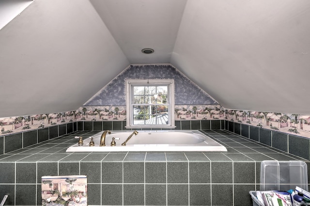 bathroom featuring a relaxing tiled tub and lofted ceiling