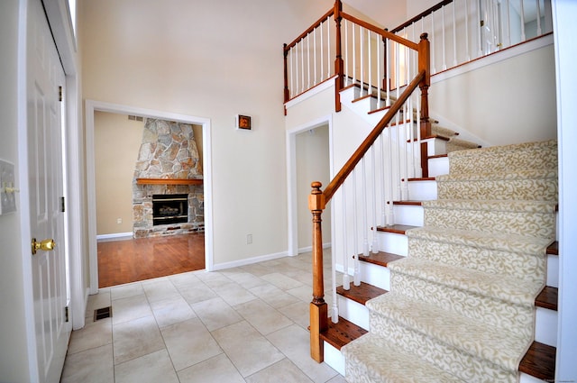 stairway with a high ceiling, tile patterned floors, and a fireplace