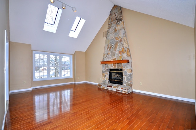 unfurnished living room featuring a stone fireplace, hardwood / wood-style floors, and high vaulted ceiling