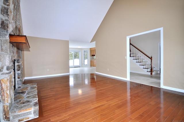 unfurnished living room with hardwood / wood-style floors, a fireplace, and high vaulted ceiling