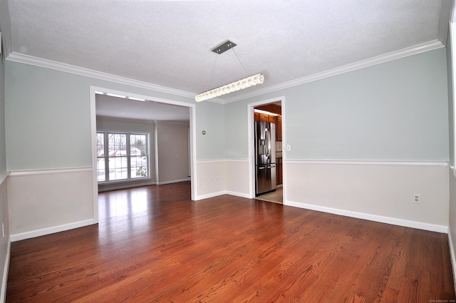 spare room featuring dark wood-type flooring, ornamental molding, and a textured ceiling