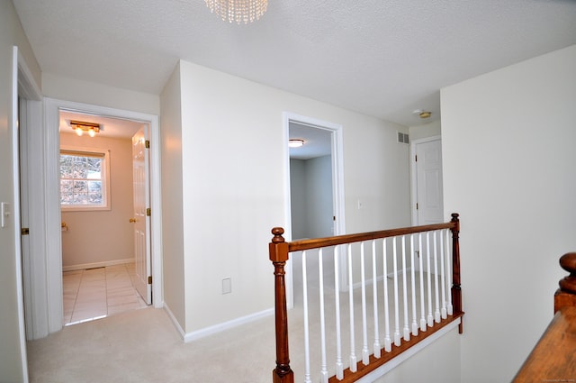 hallway featuring light carpet and a textured ceiling