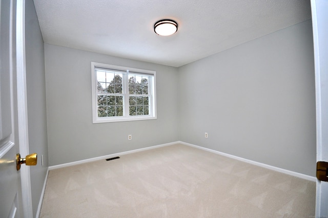 spare room featuring light carpet and a textured ceiling