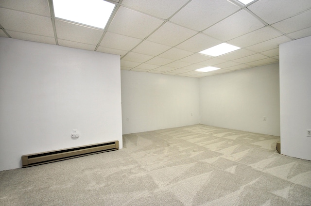 basement featuring light carpet, a paneled ceiling, and baseboard heating