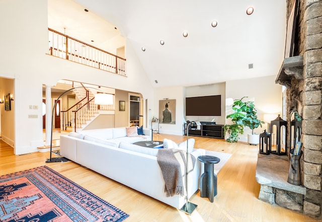 living room with ornate columns, high vaulted ceiling, and light hardwood / wood-style floors