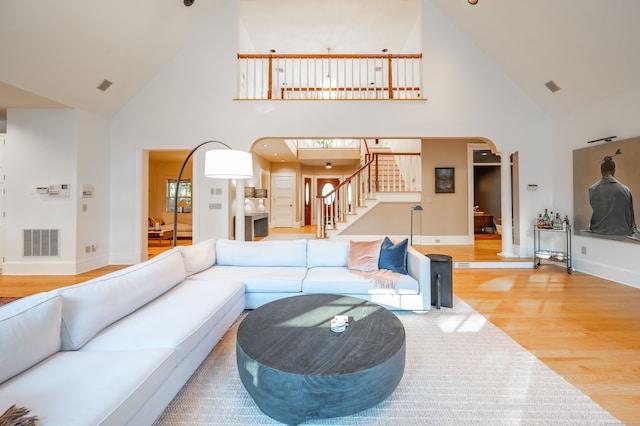 living room with wood-type flooring, ornate columns, and high vaulted ceiling