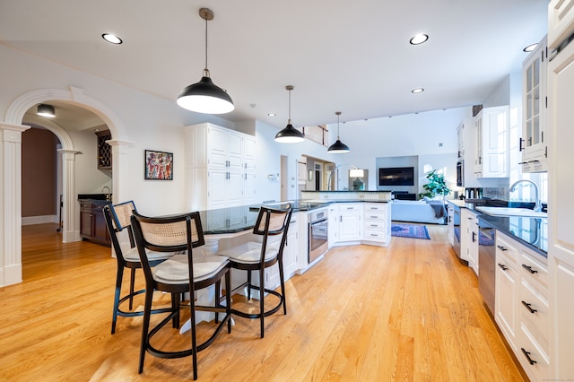 kitchen featuring appliances with stainless steel finishes, sink, a breakfast bar, white cabinets, and light hardwood / wood-style flooring