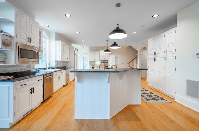 kitchen featuring stainless steel appliances, white cabinetry, sink, light hardwood / wood-style flooring, and a kitchen island