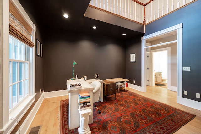 office with light wood-type flooring and a high ceiling