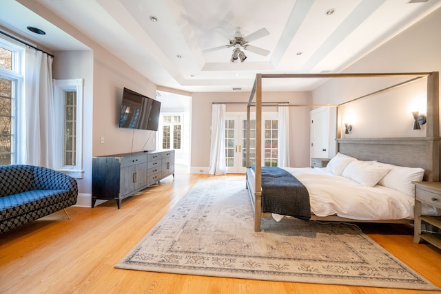 bedroom with access to exterior, light hardwood / wood-style floors, ceiling fan, and a raised ceiling