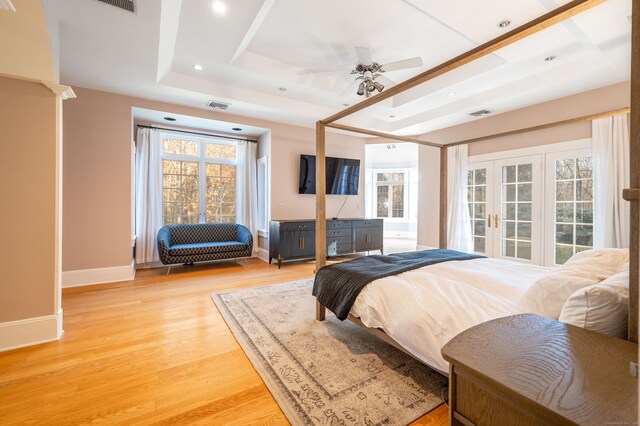 bedroom with multiple windows, hardwood / wood-style floors, ceiling fan, and a raised ceiling