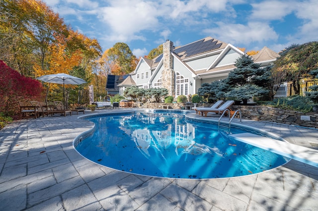 view of pool featuring a diving board and a patio area