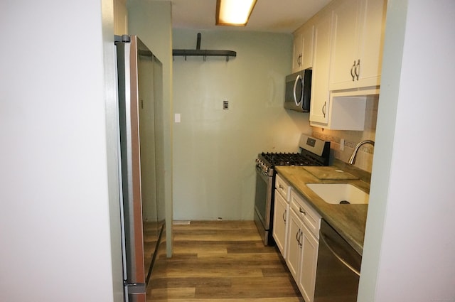 kitchen with white cabinetry, sink, decorative backsplash, appliances with stainless steel finishes, and hardwood / wood-style flooring