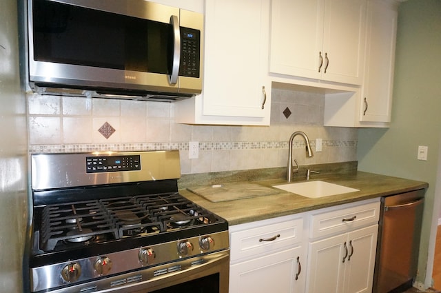 kitchen with backsplash, stainless steel appliances, white cabinetry, and sink