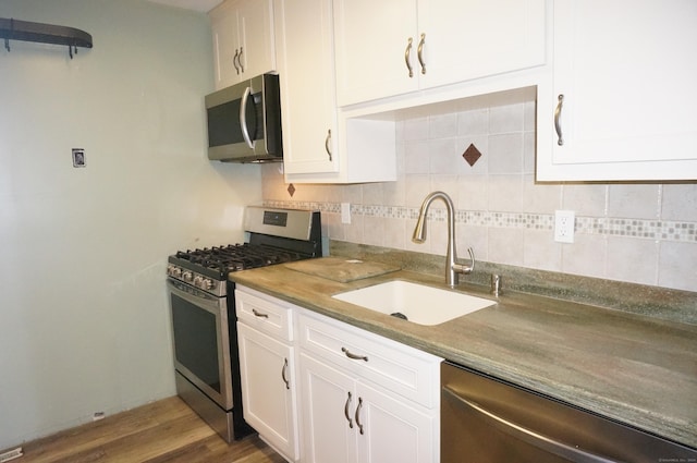 kitchen with hardwood / wood-style flooring, white cabinetry, sink, and appliances with stainless steel finishes