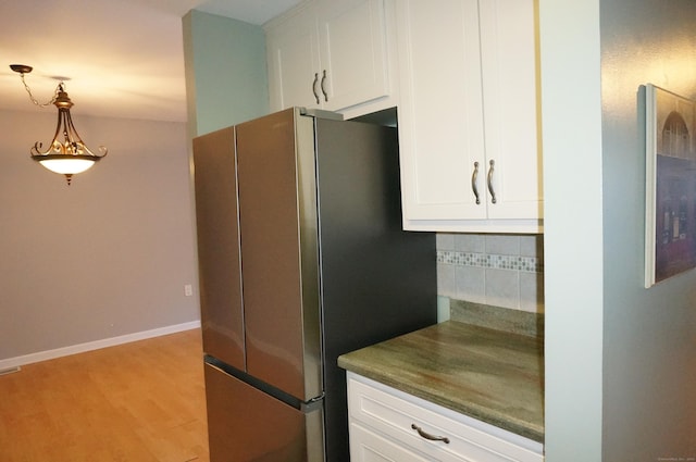 kitchen featuring white cabinets, stainless steel fridge, light hardwood / wood-style floors, and decorative light fixtures