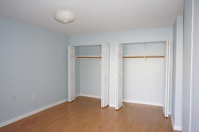 unfurnished bedroom with hardwood / wood-style floors and two closets