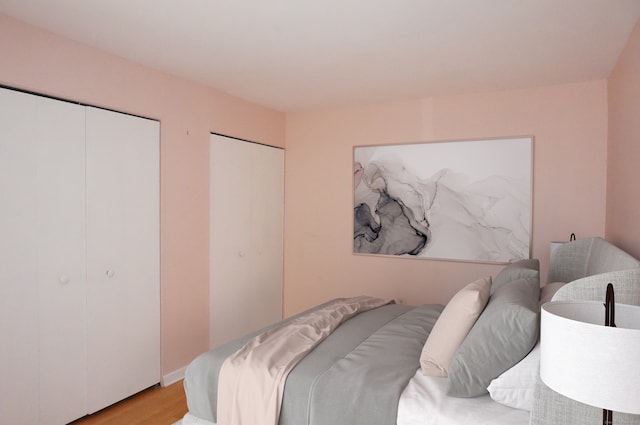 bedroom with two closets and light hardwood / wood-style floors