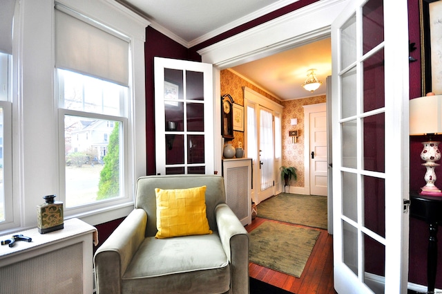 sitting room with wood-type flooring, plenty of natural light, radiator heating unit, and crown molding