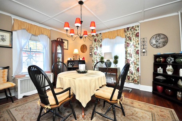 dining area with dark wood-type flooring, ornamental molding, and a notable chandelier