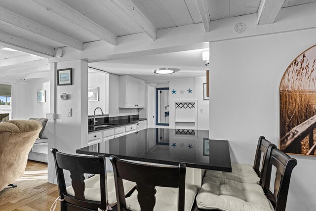 kitchen featuring beam ceiling, light wood-type flooring, white cabinetry, and sink