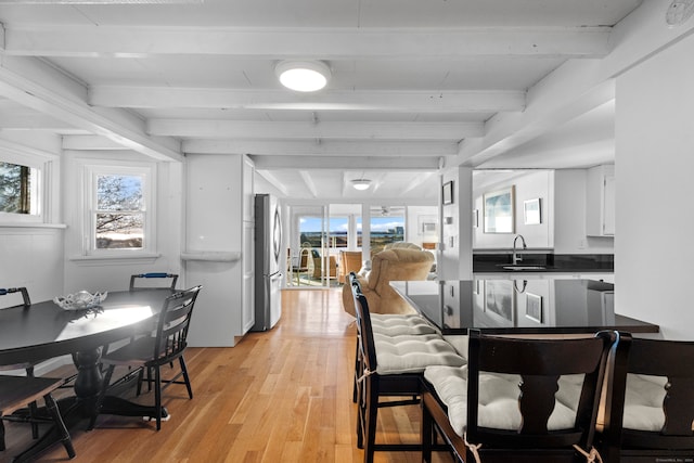 dining room featuring sink, beamed ceiling, and light hardwood / wood-style floors