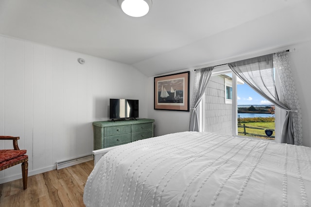 bedroom with lofted ceiling, light hardwood / wood-style floors, and a baseboard heating unit