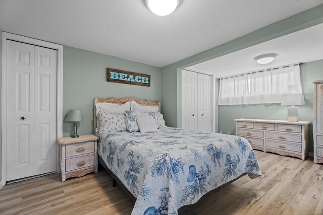 bedroom with light hardwood / wood-style floors and multiple closets